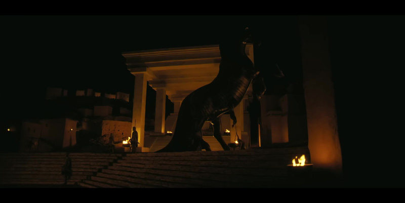 Scène nocturne de L'Odyssée de Christopher Nolan, montrant un cheval monumental devant un temple grec éclairé par des flammes.