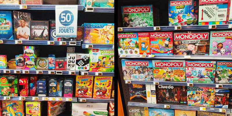 Rayons de jeux de société en grande surface, présentant notamment plusieurs éditions du Monopoly et des jeux familiaux.